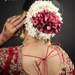 A stunning bridal bun created with a mix of fresh jasmine and rose petals. This hairstyle is a beautiful way to incorporate natural elements into your wedding day look.