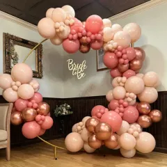 A beautiful "Bride to Be" balloon arch. The organic arrangement of blush, pink, and rose gold chrome balloons on a golden ring frame is perfect for a chic bridal shower.