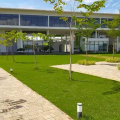 The central plaza at the DRL Leadership Academy acts as a buffer between the academic and residential zones. This large green walkway is flanked by trees and serves as the main axis of the campus.