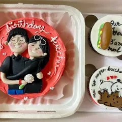 An open-box view of our custom couple-themed bento and cupcake combo. The red bento cake features a detailed fondant couple, while the cupcakes celebrate their unique bond with cute pandas and food references.