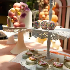 A display of delicious and artistic desserts, including a modern cake with sprinkles, cake pops, and rainbow-themed treats.