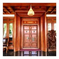 A closer look at a traditional main door design. The detailed carving, ornate metal hardware, and multi-layered wooden frame are all hallmarks of classic Kerala architecture, which we adapt for modern residences.