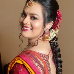 A beautiful side profile showcasing a traditional braided hairstyle. The braid is decorated with fresh flowers and a delicate hair accessory that drapes over the ear, adding a touch of elegance.