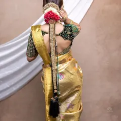 A back view of a bridal blouse made from rich velvet. The sleeves are heavily embroidered, complementing the golden Kanjeevaram saree perfectly for a luxurious Muhurtham look.