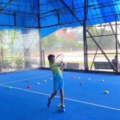 A young player perfects his forehand on our covered court. The bright blue surface and excellent lighting provide a professional training environment, protected from the elements.