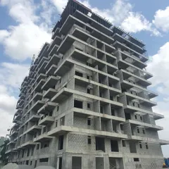 The building's structure seen from the ground level, with piles of construction materials ready for use. This is where the architectural plans begin to become a physical reality.