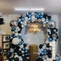 A balloon ring is a great backdrop for a first birthday cake smash or photo session. This one uses a cool color palette of blue, black, and silver, complete with a 'Happy Birthday' neon sign and a light-up number '1'.