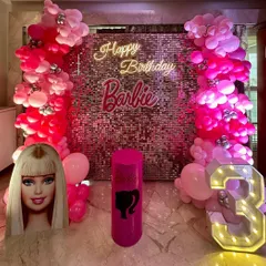 A dazzling Barbie theme birthday party perfect for a little fashionista. The decor is built around a pink sequin wall, with pink balloon columns, a "Happy Birthday Barbie" neon sign, and a large light-up number '3'.