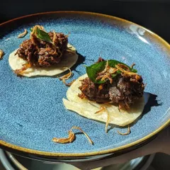 I love making traditional dishes easy to enjoy at parties. This is my Beef Ullarthu, slow roasted with coconut chips and curry leaves until it's incredibly tender, served on a bite-sized mini parotta. It’s a true taste of Kerala in one perfect bite.