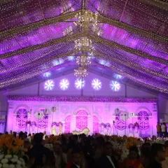 For a truly grand affair, we transformed this large tented venue with a ceiling of cascading fairy lights and magnificent chandeliers. The purple uplighting and expansive stage create a sense of awe and splendor.