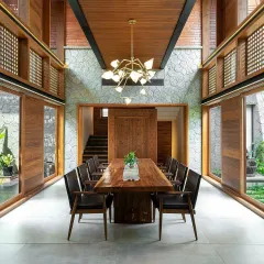 This symmetrical view highlights how our courtyard design integrates with the home's architecture. The open-air garden acts as a central lung for the house, visible through large sliding glass doors on either side of the dining area.