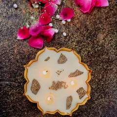 A lit mini gold Urli candle, its multiple wicks creating a beautiful, warm glow.