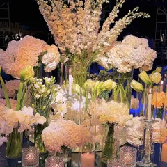 Another perspective of the abundant white floral centerpiece, capturing the soft glow of candles and the intricate layers of different flower varieties. This is where beauty creates a silent, powerful echo.