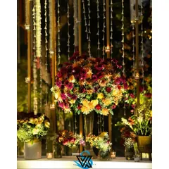A stunning, large floral centerpiece set against a backdrop of hanging flower strings and candles. This shows how we layer different elements to create a rich, multi-dimensional look.