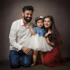 A kneeling family portrait creates a lovely, connected composition. The coordinated outfits and warm smiles make this a cherished memory.