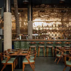 Every detail matters in creating the right mood. Here, the custom bar features a live edge wood countertop and a striking green subway tile fascia. The warm backlighting on the bottle display and the reflection on the polished columns create a sophisticated and inviting atmosphere for guests.