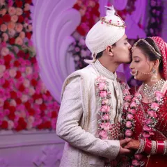 A sweet kiss on the forehead, set against a beautifully decorated floral backdrop. A perfect romantic wedding portrait.