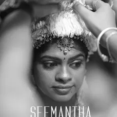 A powerful black and white close-up of a woman during her Seemantha ceremony. The focus is on her expressive face as hands perform a traditional ritual, capturing the solemnity of the moment.