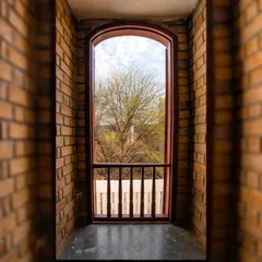 A view through an arched opening framed by walls made of stabilized earth blocks. The soil was excavated directly from the basement, making it the primary, hyper-local building material for the project.