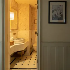 Even a small powder room can leave a big impression. This space balances style and personality, with a patterned wallpaper, a custom-printed basin, and classic black-and-white marble flooring.