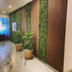 We designed this hallway by integrating vertical strips of artificial greenery with dark wood louvered panels. This combination of textures adds depth and a modern, natural feel to the commercial space.