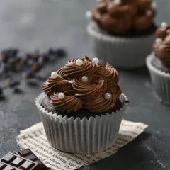 A close-up of our classic eggless chocolate cupcake. It's topped with a rich, swirled chocolate frosting and delicate pearl sprinkles for a simple and elegant finish.