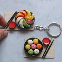 A pair of momo miniatures, one as a keychain and the other as a magnet.