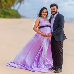 A classic pose showing the beautiful connection between the couple. This one-shoulder style of our lavender gown offers a different look, and the embellished belt adds a touch of sparkle. The partner's suit completes this polished beach photoshoot outfit.