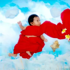 A dreamy portrait for a precious newborn. We used soft fabrics and a painted cloud backdrop to create this ethereal image, making it look as if the baby is floating peacefully in a bright blue sky.