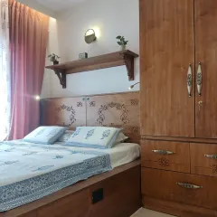 Natural light illuminates the intricate CNC-carved details on the headboard and wardrobe in this master bedroom. The design features a king-size platform bed with an extended reading area and abundant hidden storage.