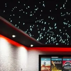 This home theater features a stunning fiber optic star ceiling and custom red ambient lighting to create a classic cinema feel. The textured acoustic wall panels not only enhance the look but also optimize the room's sound quality.