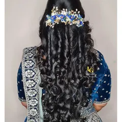 A romantic and modern hairstyle for a reception. We created soft, cascading curls and accessorized them with a beautiful blue floral clip to match the client's lehenga.