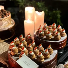 Another view of the Gajar Halwa choux pastries, beautifully arranged on a platter and lit by candlelight.