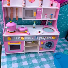 Our pink wooden pretend play kitchen, featuring a microwave, oven, sink, and a variety of pots, pans, and play food for little chefs.