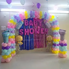 A pastel-colored balloon arch for a baby shower. The decoration includes "It's a Boy" and "It's a Girl" foil balloons on pillars, along with baby-themed foil balloons, keeping the gender a surprise.