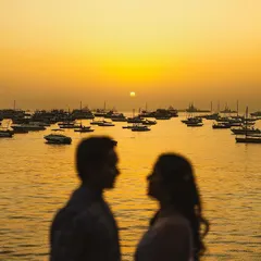 Capturing the iconic Mumbai sunrise over the harbour. The silhouette of the couple against the golden sky and the fleet of boats creates a timeless and romantic image of the city.