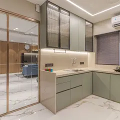 This modern kitchen features custom sage green cabinetry and a functional L-shaped layout. We used fluted glass on the upper cabinets and integrated lighting to create a bright, stylish, and highly practical workspace that opens into the main living area.
