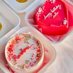 A coordinated set of birthday bento cakes. This collection includes a personalized name cake with sprinkles, a heart-shaped message cake, and a cherry-topped cake, perfect for a group celebration.