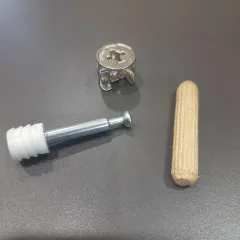 We teach modern assembly methods alongside traditional ones. This image shows the components of a mini-fix system and a wooden dowel, which are essential hardware for building sturdy, ready-to-assemble modular furniture.