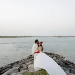 A dramatic portrait on the shores of Abu Dhabi. The flowing white dress against the rocks and water creates a powerful, high-fashion image.