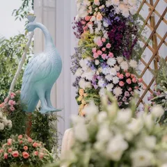 A pastel-themed Mehendi with an 'Alice in Wonderland' touch. The decor features whimsical elements like a pastel blue peacock and an abundance of soft-hued flowers.