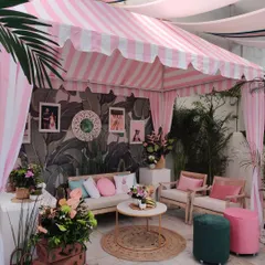 The full view of our custom-built Gray Malin inspired cabana. The pink and white striped awning and lush tropical plants created the perfect retro-chic photo corner.