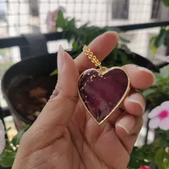 A close-up of the heart-shaped pendant with preserved rose petals. The gold-plated bezel and chain complement the rich color of the flowers perfectly.