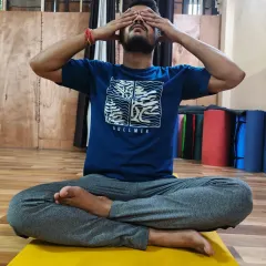 A male student practices Bhramari Pranayama, demonstrating the Shanmukhi Mudra to close off the senses. This helps to turn the awareness inward, deepening the meditative experience.