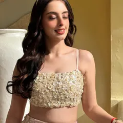 A sun-kissed shot of Yashodhra Seth. Her hair is styled in deep, glossy waves that catch the light beautifully, a perfect example of a glamorous open hairstyle.