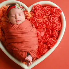 A peacefully sleeping baby, nestled amongst soft roses. This is the heart of my classic newborn sessions. I use simple, beautiful props like this heart-shaped basket to create a timeless portrait where your baby's innocence is the true centerpiece.