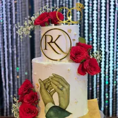A beautiful two-tier engagement cake featuring fresh red roses, a custom 'RK' monogram, and a unique edible image of the couple's hands. I love adding these personal details that tell a story.