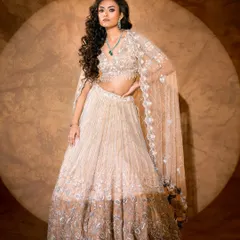 Ethereal elegance brought to life. This full-length shot showcases the delicate craftsmanship of a silver and beige lehenga, using soft lighting to create a dreamy, romantic mood perfect for a luxury lookbook.