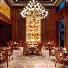 A dining area within the Sheraton Hotel, where a dramatic chandelier hangs above a backlit onyx wall feature. The combination of dark wood and warm light creates an elegant and intimate dining experience.
