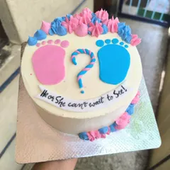 "He or She, can't wait to see." This cute gender reveal cake features pink and blue baby footprints and piped buttercream swirls to build the anticipation.